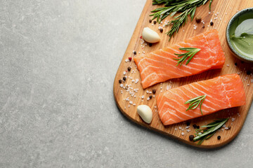 Fresh raw salmon and spices on light grey table, top view. Space for text