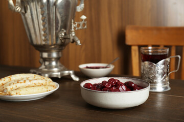 Vintage samovar, cup of hot drink and snacks served on wooden table. Traditional Russian tea ceremony