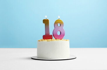 Coming of age party - 18th birthday. Delicious cake with number shaped candles on light blue...