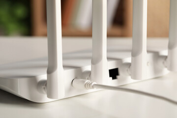 New Wi-Fi router on white table indoors, closeup