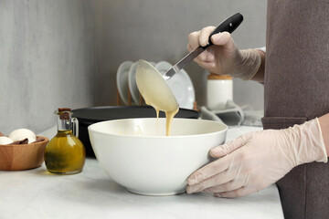 Woman cooking delicious crepe at white marble table in kitchen, closeup