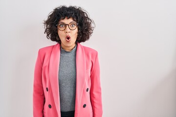 Hispanic woman with curly hair standing over isolated background afraid and shocked with surprise expression, fear and excited face.