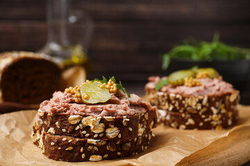 Delicious liverwurst sandwiches with pickled cucumber and mustard on wooden board, closeup