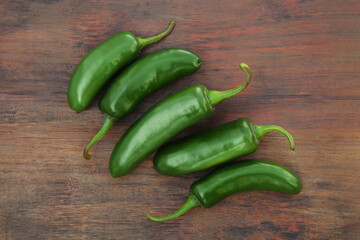 Fresh green jalapeno peppers on wooden table, flat lay