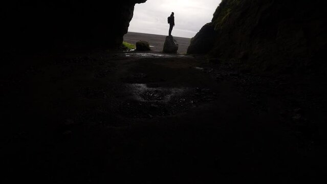 Tilt Shot Of A Man Standing At Gigjagja Cave's Entrance
