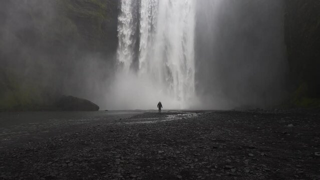 Man Walking At The Center Of Skogafoss Waterfall
