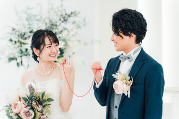 結婚式場で赤い糸で結ばれる新郎新婦（ブライダル・ウェディング）
