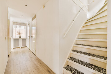 a hallway with stairs and wood flooring on the side, leading up to an open door that leads to...