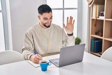 Young handsome man using computer laptop doing online call looking positive and happy standing and...