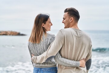 Man and woman couple smiling confident hugging each other at seaside