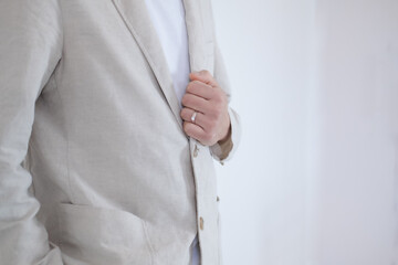 The groom wears a ring and holds his shirt on his wedding day.