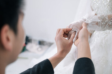 bride and groom holding hands and wearing a wedding ring.