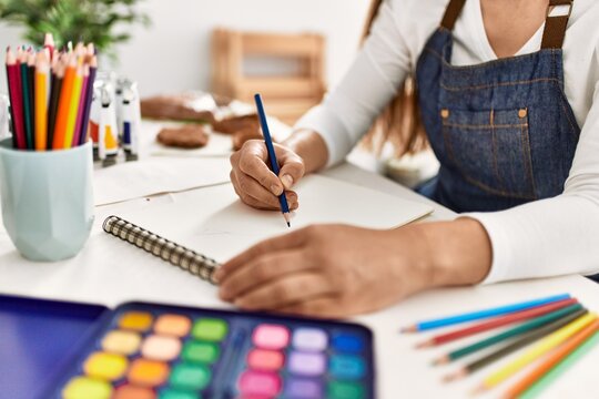 Young caucasian woman drawing on notebook at art studio