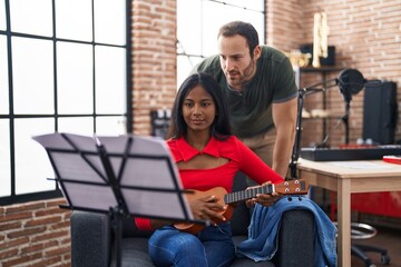 Man and woman musicians playing ukulele at music studio