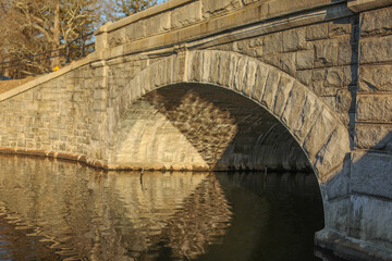 bridge showing sunset and water through old stone  © Your Hand Please