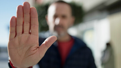 Middle age man doing stop gesture with hand at street