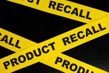 Product recall alert, caution and warning concept. Yellow barricade tape with word in dark black...