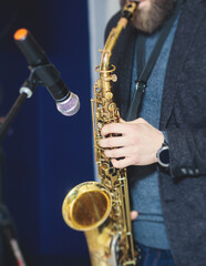 Concert view of saxophonist, a saxophone sax player with vocalist and musical band during jazz orchestra show performing music on a stage in the scene lights