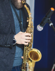 Obraz premium Concert view of saxophonist, a saxophone sax player with vocalist and musical band during jazz orchestra show performing music on a stage in the scene lights