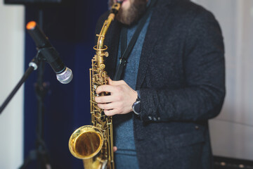 Naklejka premium Concert view of saxophonist, a saxophone sax player with vocalist and musical band during jazz orchestra show performing music on a stage in the scene lights