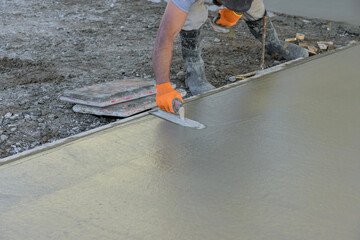 Using trowel worker plasters wet concrete cement floor after it has been poured - obrazy, fototapety, plakaty