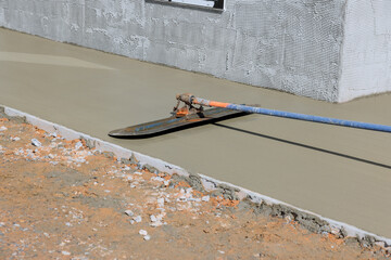 Worker plasters wet concrete floor using trowel after pouring concrete on surface