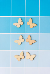 six wood butterfly cutout ornaments on blue paper sheet with paint-chip coloration