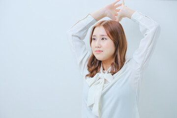 Fototapeta premium 体操をする白いブラウス姿の若い女性