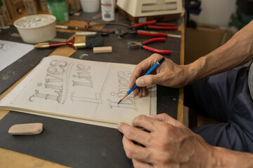 man drawing at home sitting in his concentrated glass workshop with all his work tools