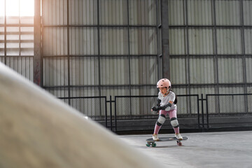 asian child skater or kid girl playing skateboard or ride surf skate up to wave ramp or wave bank...