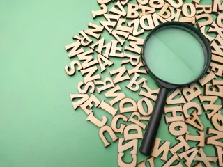 Fotobehang Wooden word and magnifying glass on a green background © Mohd Azrin
