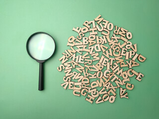 Wooden word and magnifying glass on a green background