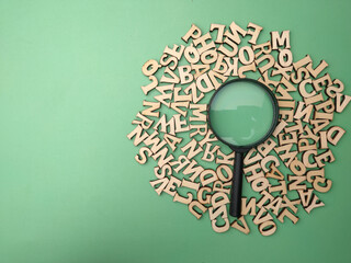 Wooden word and magnifying glass on a green background