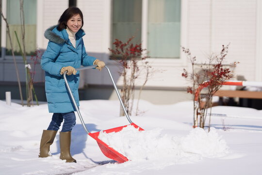 雪掻きをする中年女性