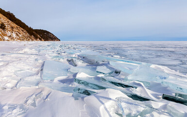 Scenic winter landscape of frozen Baikal Lake with blue ice floes and ice hummocks on a cold January day. Natural winter background