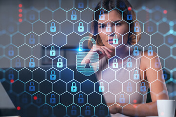 Thoughtful businesswoman in casual wear typing on laptop at office workplace with coffee cup. Concept of distant work, business education, internet surfing, information technology. Lock hologram