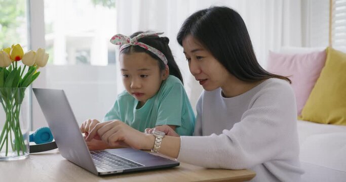 Cute asia people alpha small Gen Z kid fun talk play learn on smart tablet app game with mum at home sofa. Enjoy Child care little girl and mom happy smile relax teach study upskill idea online class.
