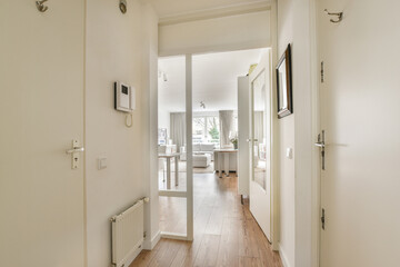 a hallway in a house with wood flooring and white paint on the walls, there is an open door leading...