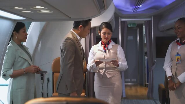 Passengers boarding the plane with boarding pass checked by flight attendants while welcoming at plane entrance. Concept of airline, business, transportation and multiracial stewardess on aircraft.