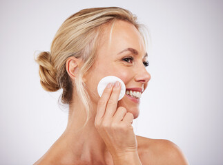 Face, cotton and skincare with a mature woman in studio on a gray background cleaning her skin for exfoliation. Relax, luxury and product with a female using a pad to cleanse her pores for beauty © Nina L/peopleimages.com