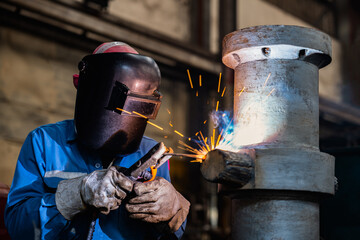 Industrial welder welding fabricated construction in factory, Welding process by Shielded Metal Arc Welding (SMAW) or Stick Welding.