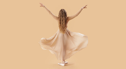 Fototapeta premium Dancing young ballerina on beige background, back view
