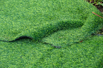 An incomplete green artificial turf used for covering sport arena or garden.