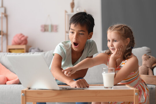 Surprised little boy and girl watching cartoons on laptop at home