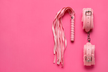 Handcuffs and whip from sex shop on pink background