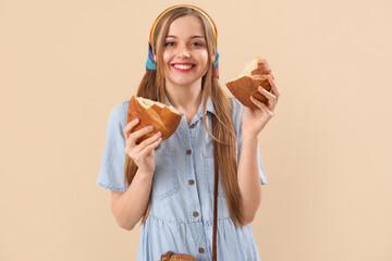 Young woman with fresh bread on beige background