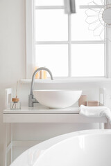 Interior of bathroom with ceramic sink and reed diffuser near window