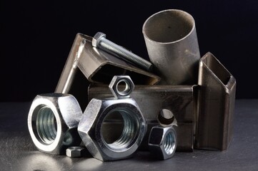 composition of nuts bolts and scraps of metal laid out on a dark background.