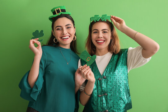 Young women with paper clover and hat on green background. St. Patrick's Day celebration