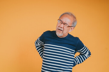 Asian senior man feeling backache or back pain on the yellow background.